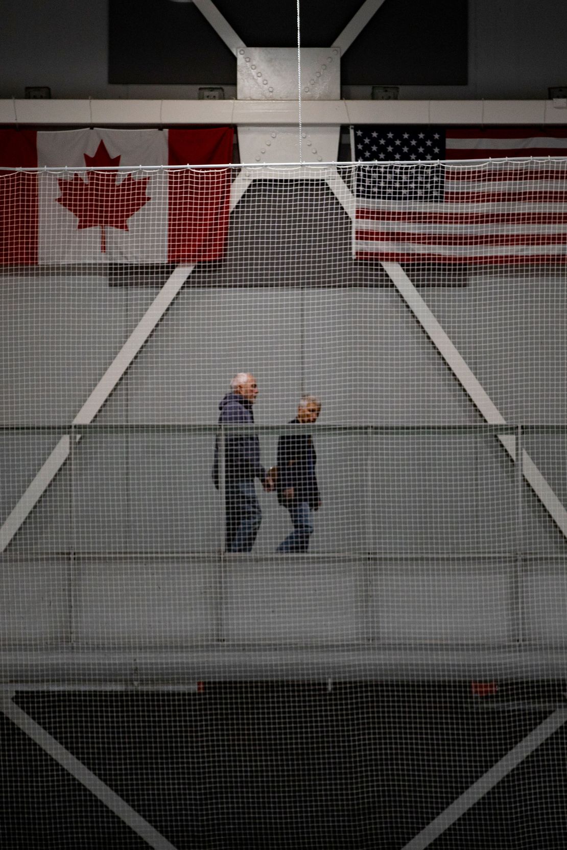 A couple walks in front of Canadian and American flags at the Wayne Gretzky Sports Centre.