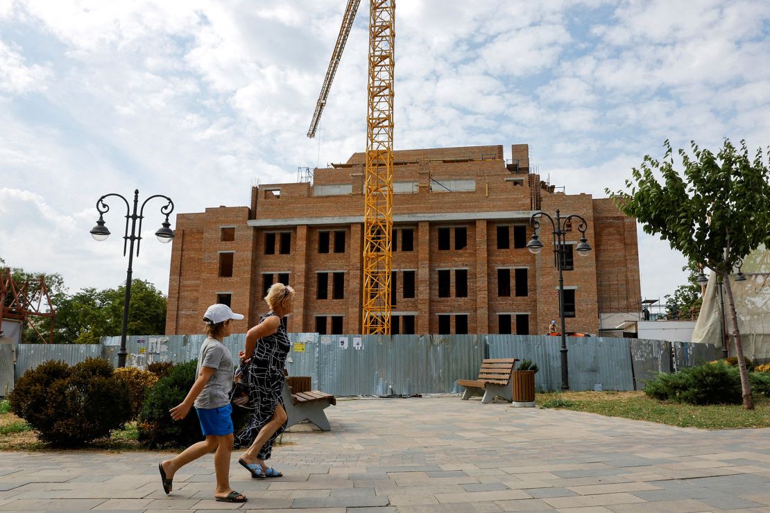 People walk past construction at the Mariupol Drama Theater on August 28, 2024.
