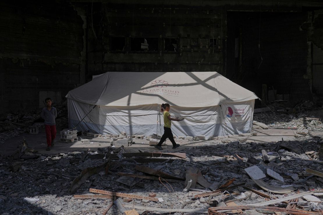 A child carries a tray of food past a tent sheltering displaced Palestinians inside the destroyed Rashad Al-Shawa Cultural Center in Gaza City on April 21.